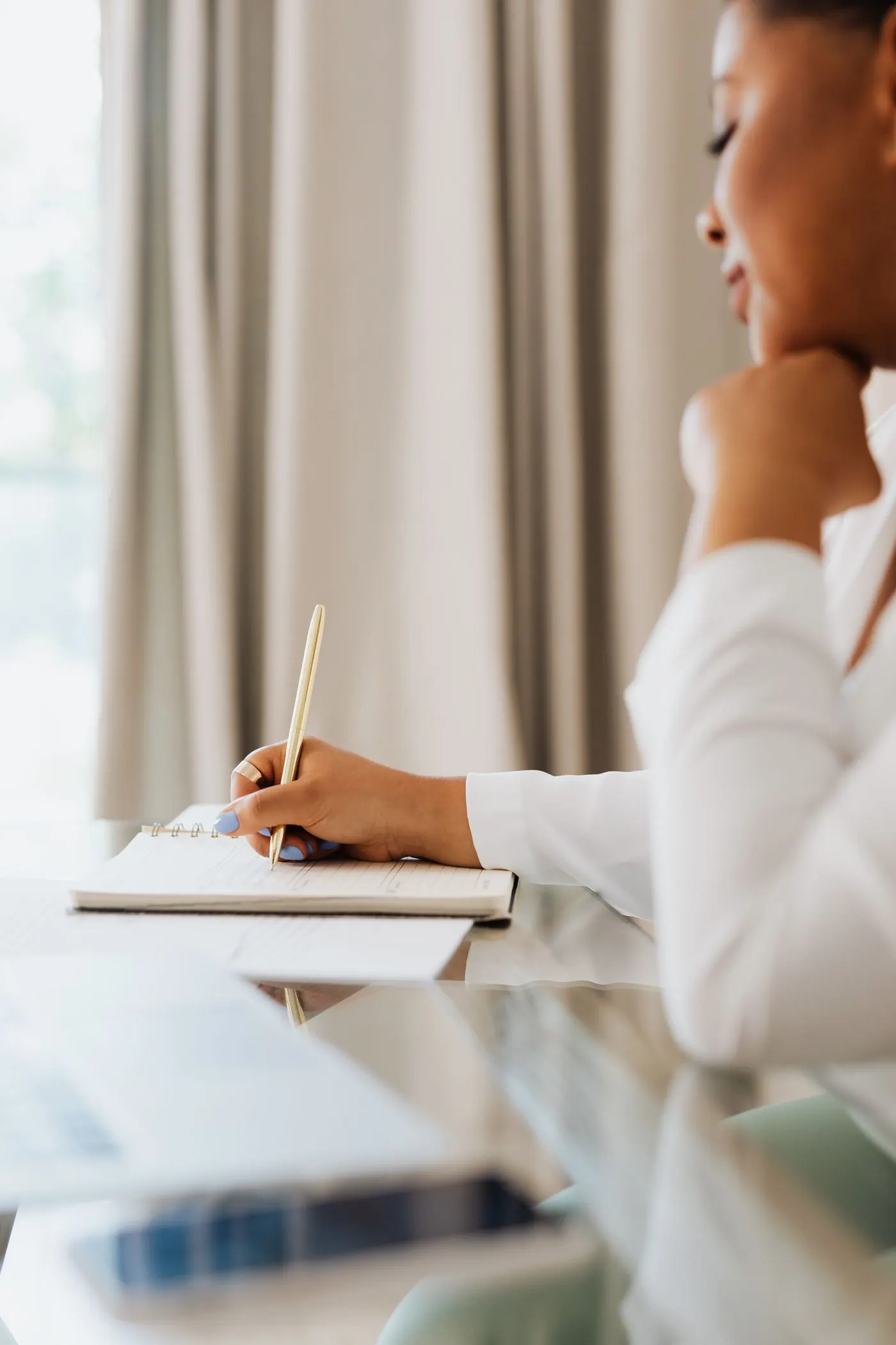 A hand writing in a notebook at a table