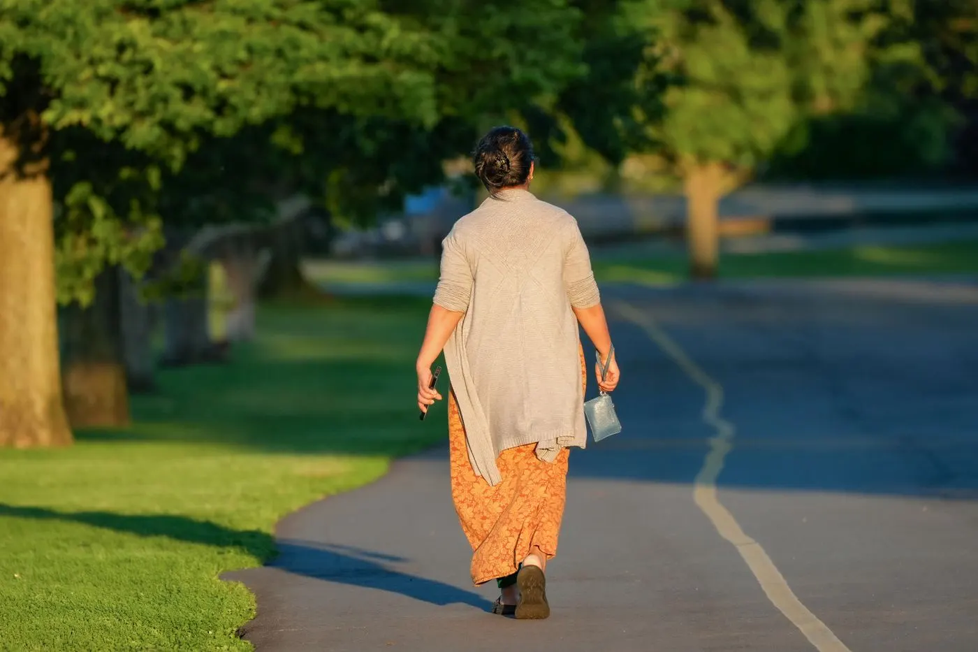 A woman walking along a sunny park path